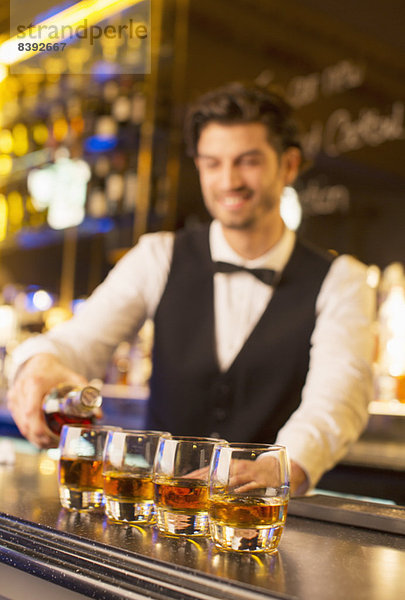 Gut gekleideter Barkeeper mit Bourbon in der Luxusbar