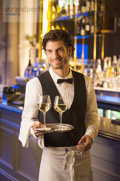 Gut gekleideter Barkeeper mit Weingläsern auf Tablett in der Luxusbar