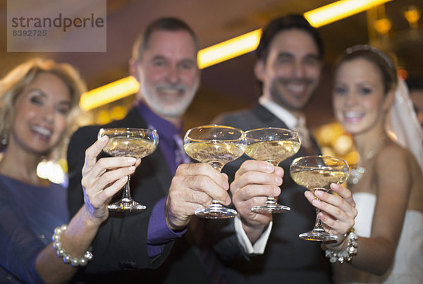 Porträt der Braut und des Bräutigams  die mit den Eltern auf Champagner trinken.