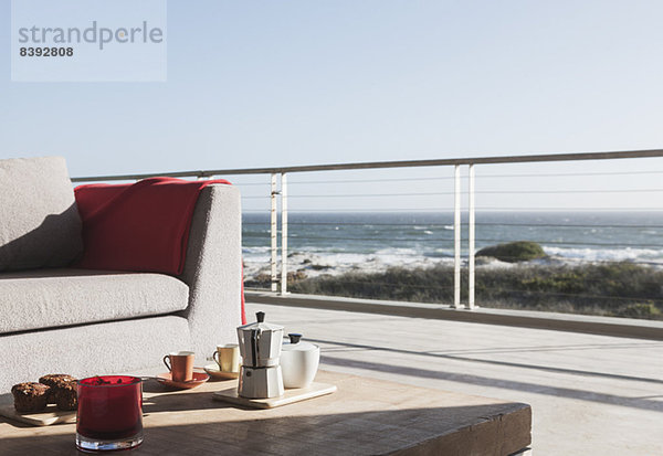 Frühstück auf dem Couchtisch auf der modernen Terrasse mit Blick auf den Ozean