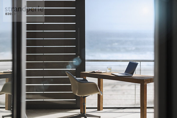 Schreibtisch und Stuhl im modernen Home-Office mit Blick auf den Ozean