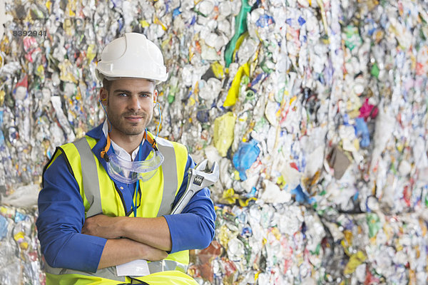 Arbeiter steht an verdichteten Recycling-Bündeln