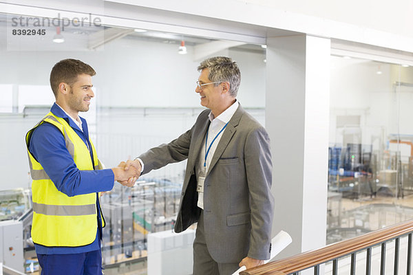 Supervisor und Arbeiter beim Händeschütteln in der Fabrik