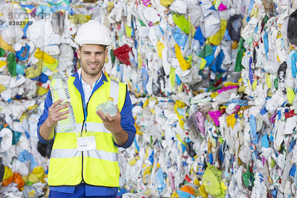 Arbeiter hält verdichtete Kunststoffflasche im Recycling-Zentrum