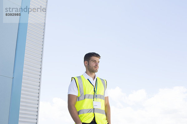 Arbeiter steht unter dem Hochhaus