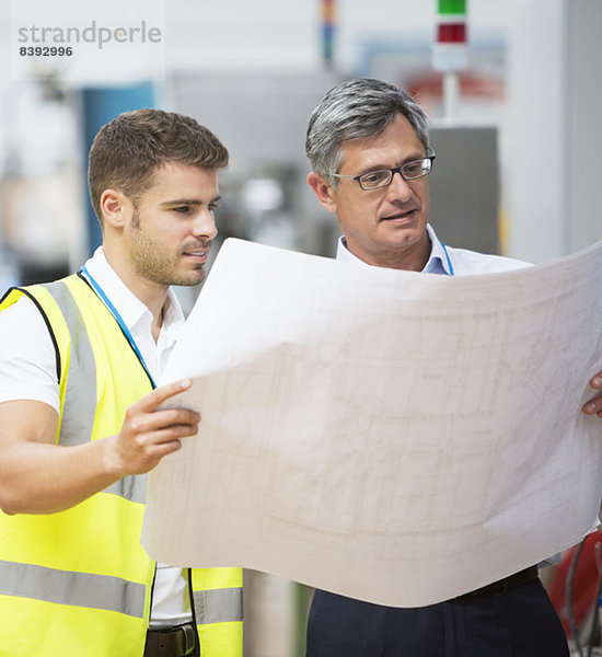 Arbeiter beim Betrachten von Bauplänen in der Fabrik