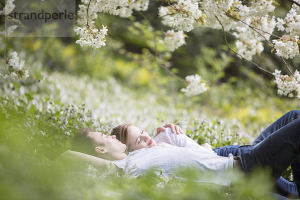 Paarverlegung im Gras unter Baum mit weißen Blüten