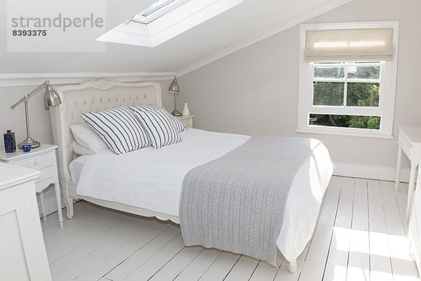 Bett im weiß getünchten Dachgeschoss-Schlafzimmer