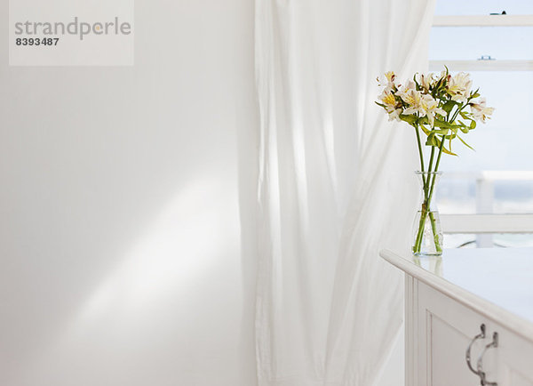 Blumenvase auf dem Schreibtisch im weißen Zimmer