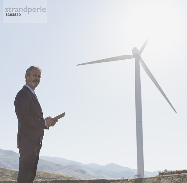 Geschäftsmann bewundert Windkraftanlage in ländlicher Landschaft