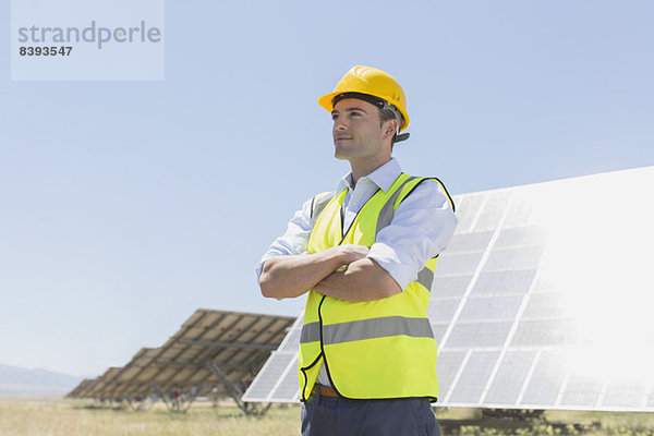 Arbeiter steht an Solarmodulen in ländlicher Landschaft