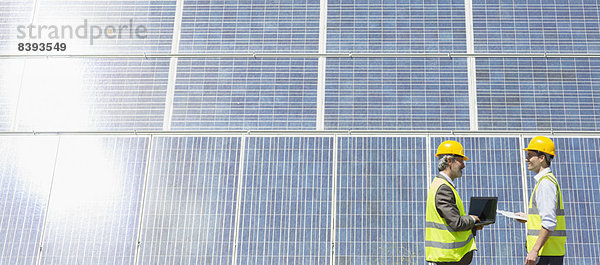 Arbeiter untersuchen Solarmodule in ländlicher Landschaft