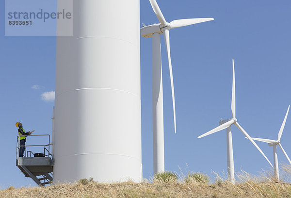 Arbeiter untersucht Windkraftanlage in ländlicher Landschaft