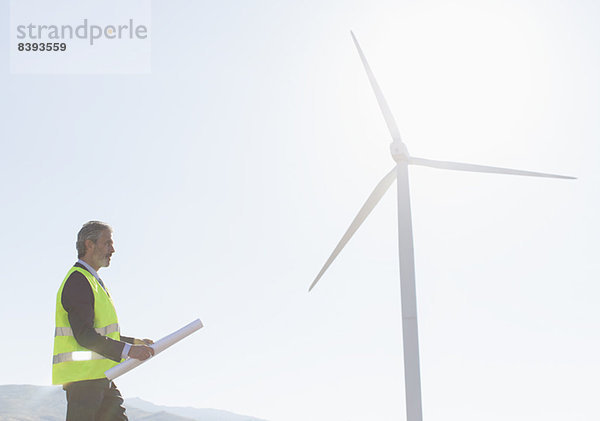 Arbeiter steht an der Windkraftanlage in ländlicher Landschaft