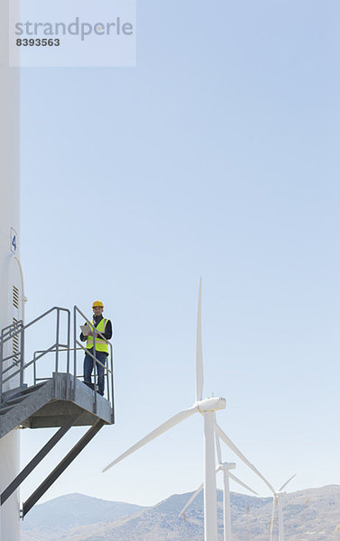 Arbeiter auf einer Windkraftanlage in ländlicher Landschaft stehend