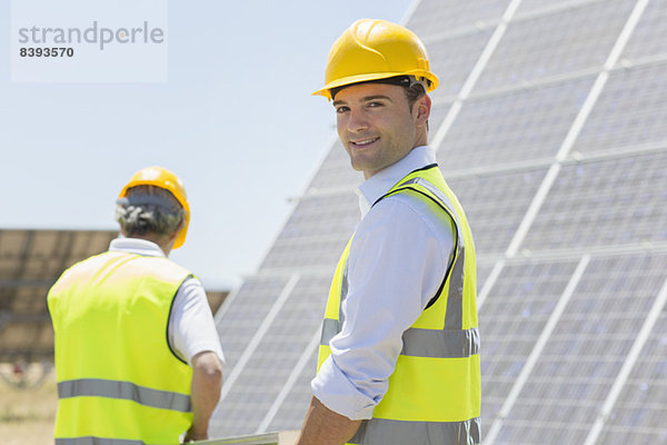 Arbeiter  die durch Sonnenkollektoren in ländlicher Landschaft laufen