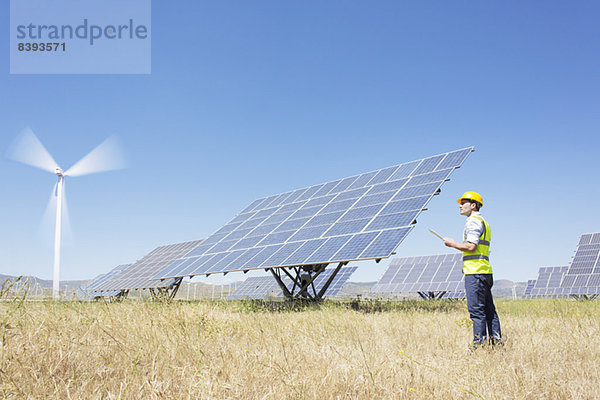 Arbeiter bei der Untersuchung von Solarmodulen in der ländlichen Landschaft