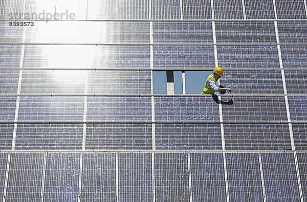 Arbeiter untersucht Solarmodul in ländlicher Landschaft