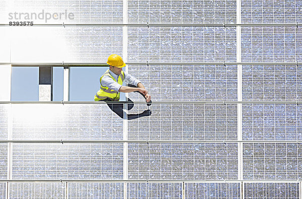 Arbeiter untersucht Solarmodul in ländlicher Landschaft