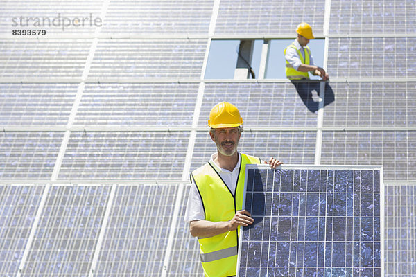 Arbeiter mit Solarmodul in ländlicher Landschaft