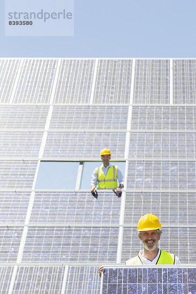 Arbeiter mit Solarmodul in ländlicher Landschaft