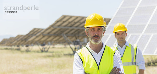 Arbeiter stehen an den Solarmodulen in der ländlichen Landschaft