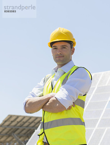 Arbeiter steht an Solarmodulen in ländlicher Landschaft