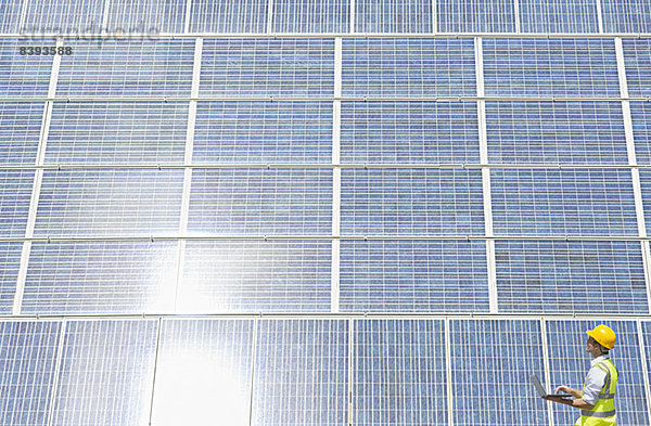 Arbeiter untersucht Solarmodul in ländlicher Landschaft