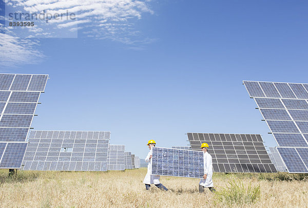 Wissenschaftler mit Solarmodul in ländlicher Landschaft