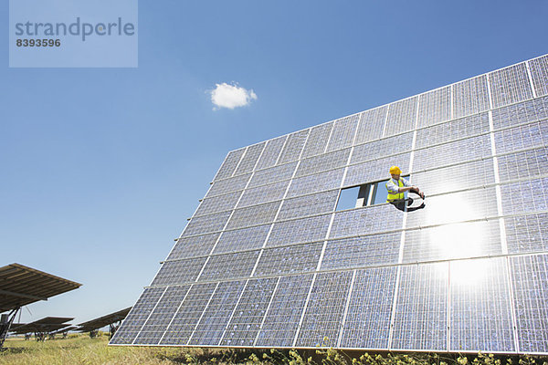 Arbeiter untersucht Solarmodul in ländlicher Landschaft