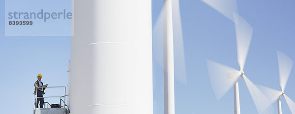 Arbeiter auf einer Windkraftanlage in ländlicher Landschaft stehend