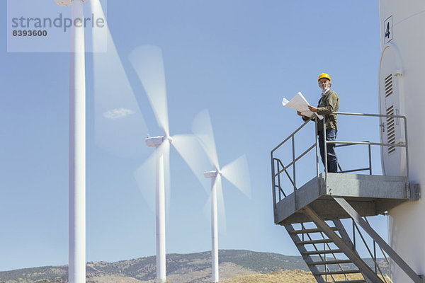 Arbeiter auf einer Windkraftanlage in ländlicher Landschaft stehend