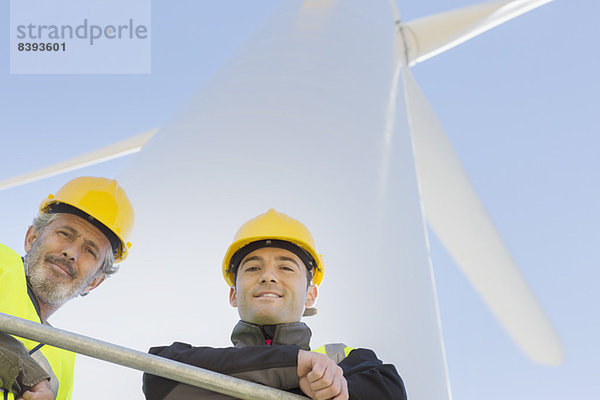 Arbeiter  die auf einer Windkraftanlage in ländlicher Landschaft stehen