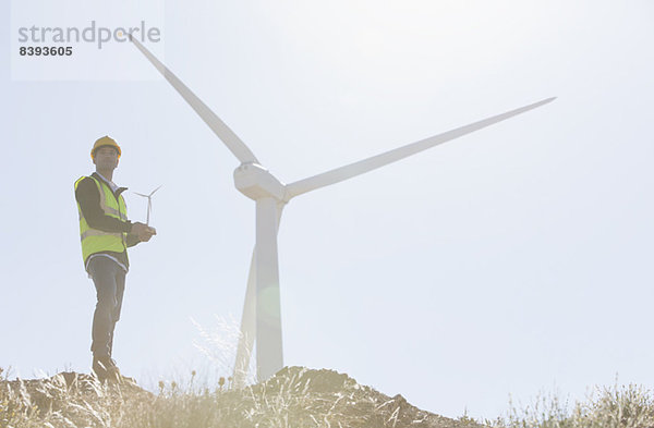 Arbeiter steht an der Windkraftanlage in ländlicher Landschaft