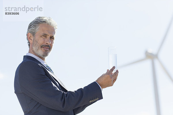 Geschäftsmann mit Glas Wasser durch Windkraftanlage