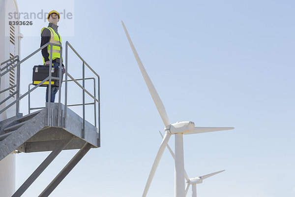 Arbeiter auf einer Windkraftanlage in ländlicher Landschaft stehend