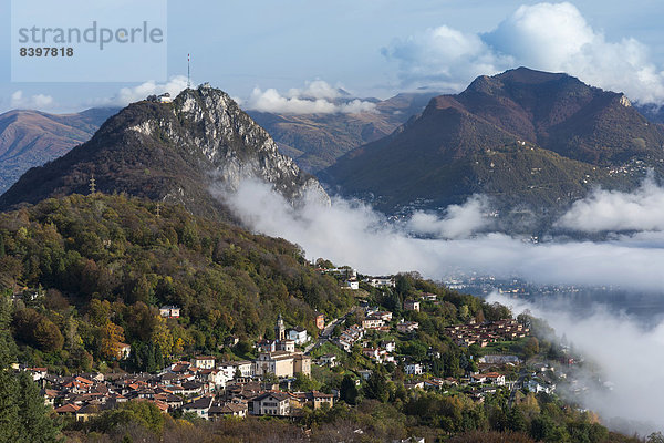 Berg Reise Morgen über See Nebel frontal Dorf Herbst Lugano Schweiz Kanton Tessin