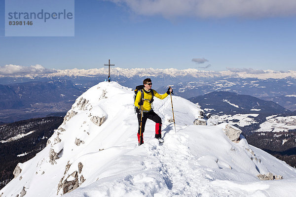 Winterwanderer am Gipfelgrat beim Abstieg vom Weißhorn am Jochgrimm  hinten der Gipfel des Weißhorn  unten das Überetsch  Südtirol  Italien
