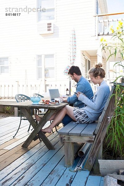 Paar auf der Terrasse mit Laptop und Handy  Breezy Point  Queens  New York  USA