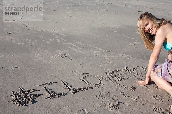 Junge Frau schreibt Liebesbotschaft in Sand  Breezy Point  Queens  New York  USA