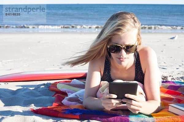 Junge Frau beim Betrachten des digitalen Tabletts am Strand  Breezy Point  Queens  New York  USA