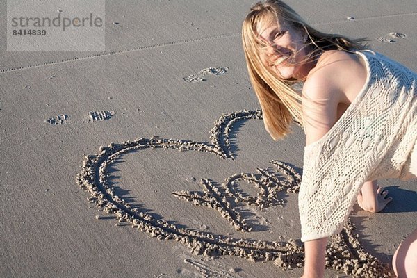 Lächelnde Frau schreibt Liebesbotschaft in Sand  Breezy Point  Queens  New York  USA