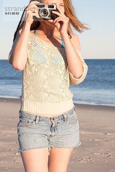 Junge Frau mit Kamera am Strand  Breezy Point  Queens  New York  USA