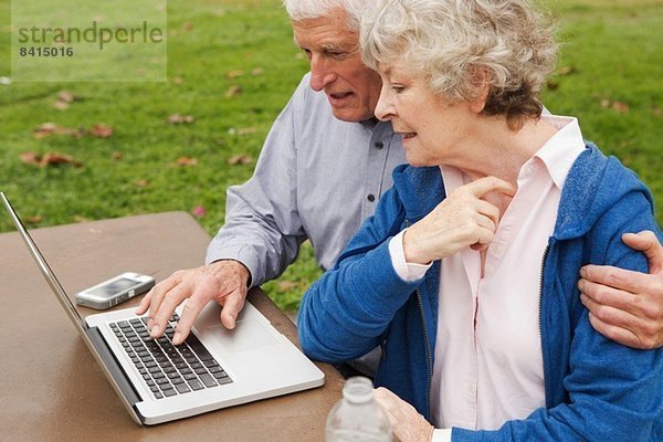 Ehemann und Ehefrau lernen den Umgang mit dem Laptop im Park