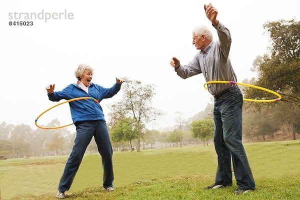 Mann und Frau spielen Hula Hoop im Park