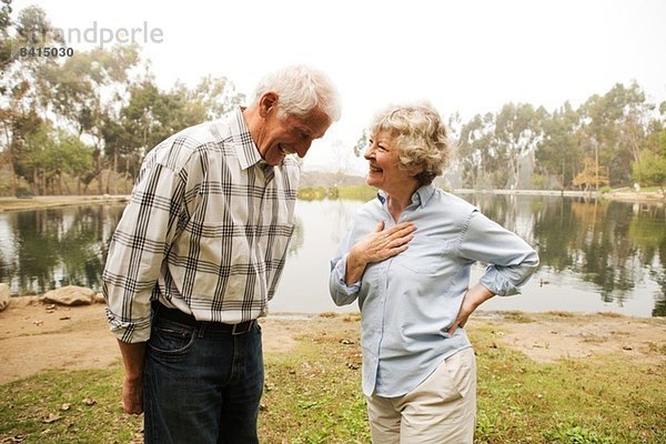 Mann und Frau teilen sich einen Witz am See.