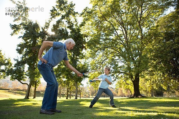 Großvater und Enkel im Spielkampf mit Spielzeugschwertern