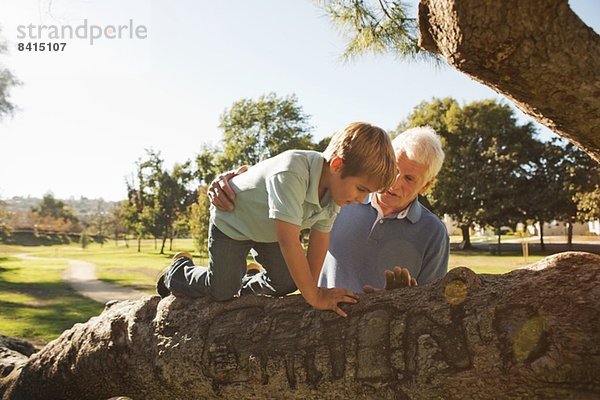 Großvater hilft Enkel beim Baumklettern