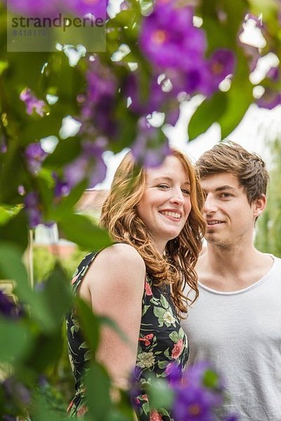 Porträt eines jungen Paares umgeben von Laub und Blumen