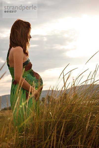 Schwangere Frau im Feld stehend